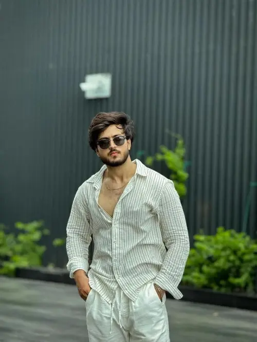 Candid Sunlit Industrial Corrugated Wall Portrait of Young South Asian Man with Sunglasses in Striped Linen Shirt and Wh — AI Photo Editing Prompt on Faymas